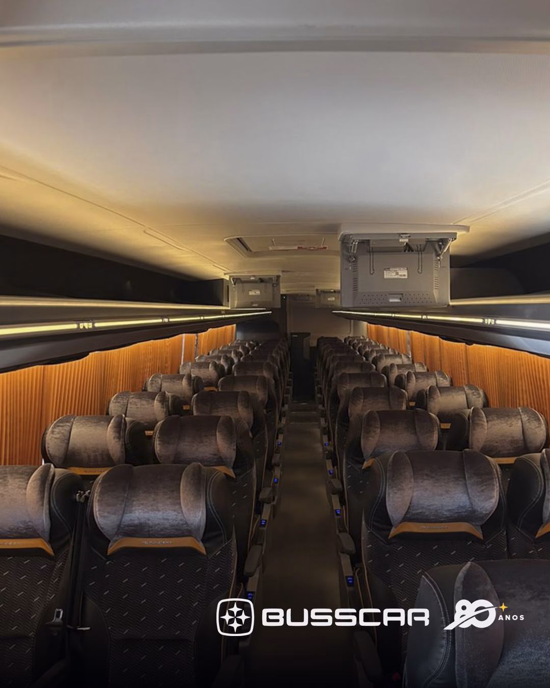 Salão de passageiros do Busscar Panorâmico 410 NB1 visto do corredor central, com poltronas em fileiras duplas dos dois lados e o corredor seguindo plano até o fundo, sem degrau visível