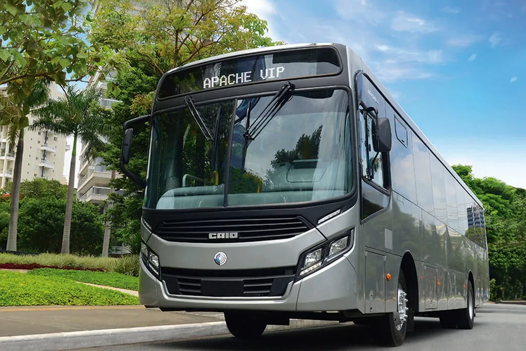 Ônibus urbano Caio Apache VIP cinza, visto de frente em três quartos, numa rua arborizada
