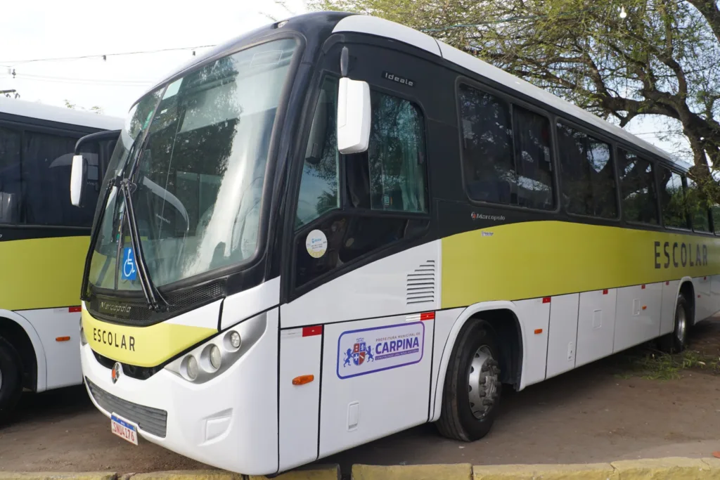 Ônibus escolar Marcopolo Ideale branco, preto e amarelo-esverdeado, com a marca da Prefeitura de Carpina na lateral, visto de frente em três quartos