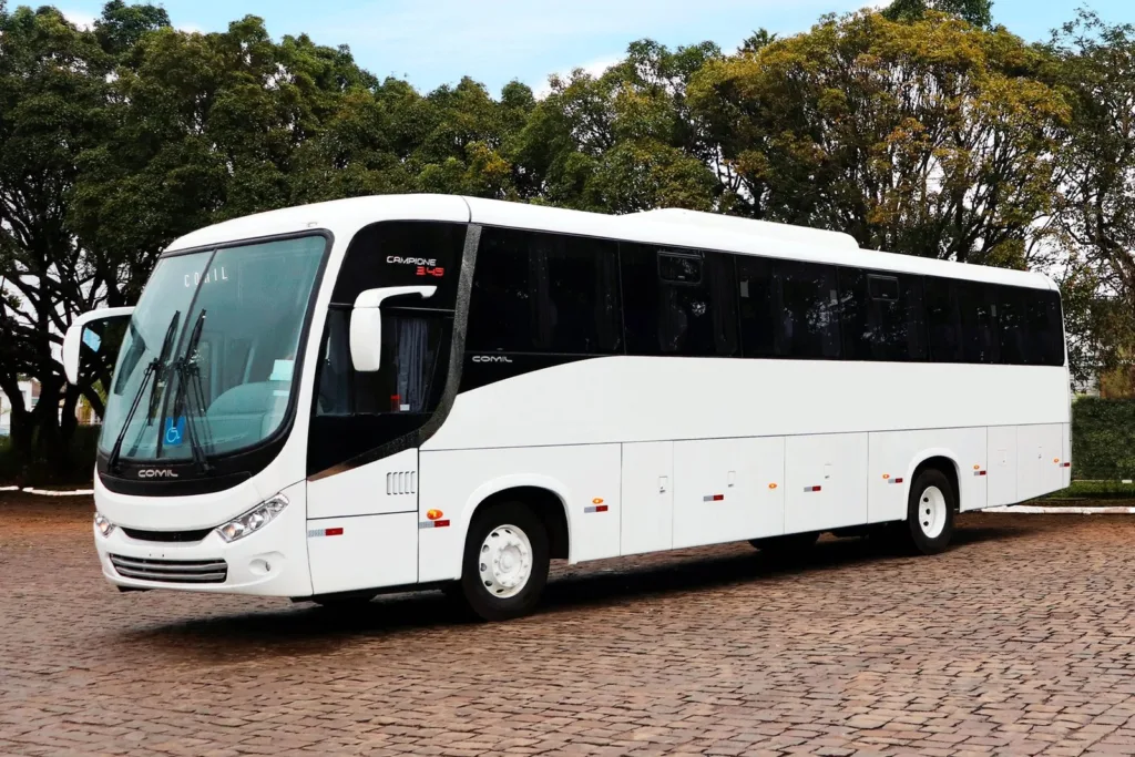 Ônibus rodoviário Comil Campione 3.45 branco, de três eixos, visto de frente e de lado em pátio calçado