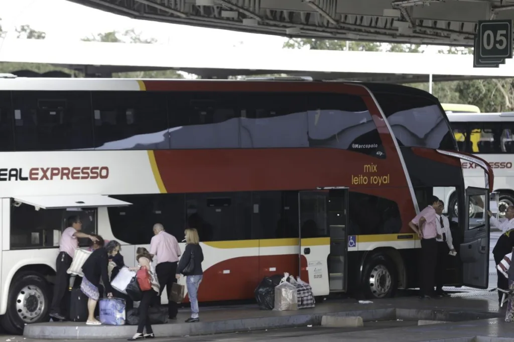 Passageiros com malas embarcam em ônibus rodoviário de dois andares com o bagageiro aberto, na Rodoviária Interestadual de Brasília
