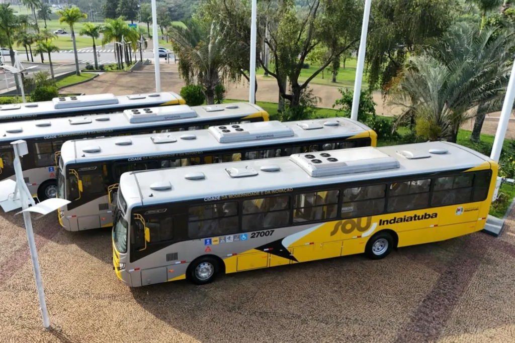 Vista aérea de quatro ônibus urbanos amarelos e cinza do transporte coletivo de Indaiatuba, alinhados em praça