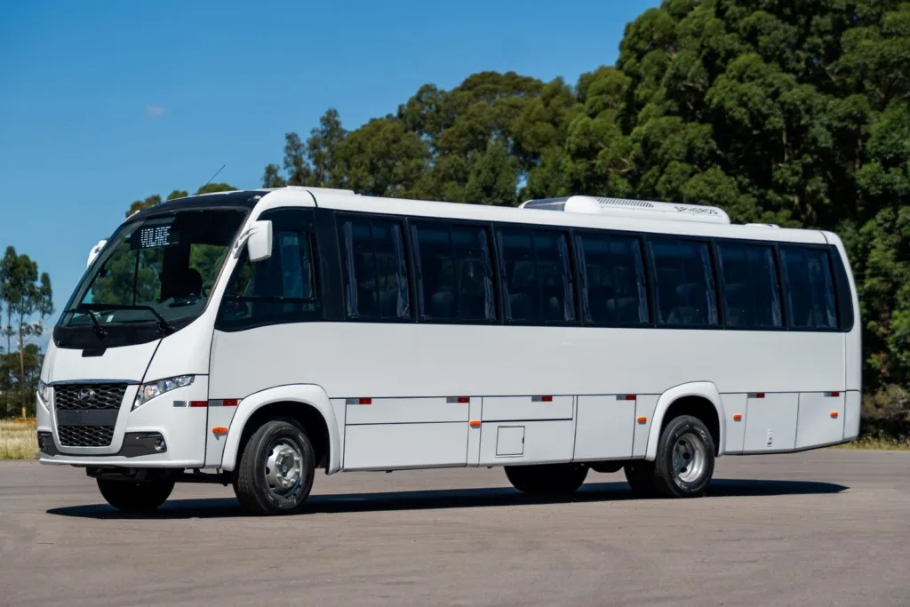 Micro-ônibus Volare Fly 10 GV branco, visto em três quartos dianteiro, em estrada sob céu azul