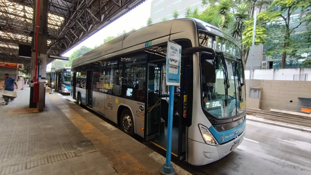 Urbano de piso baixo a bateria, um dos ônibus elétricos em São Paulo, parado em terminal com passageiros embarcando.