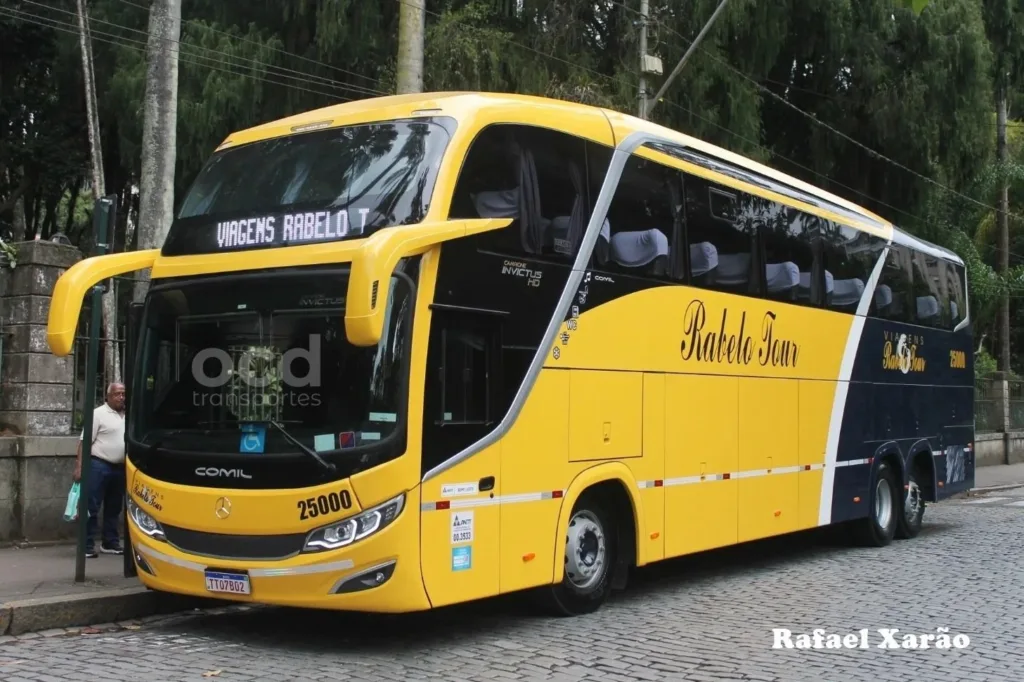 Ônibus rodoviário Comil Invictus amarelo e azul da Rabelo Tour, vista três quartos dianteira, em rua de calçamento