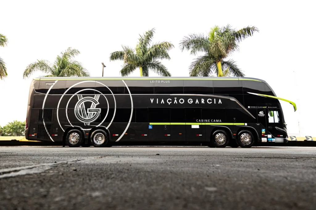 Ônibus Marcopolo Paradiso G8 1800 DD preto com detalhes verde-limão da frota da Viação Garcia, visto de lado, com palmeiras ao fundo