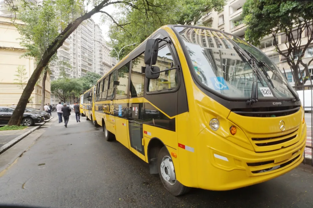Fila de ônibus novos amarelos alinhados numa rua, na entrega de frota a municípios paulistas